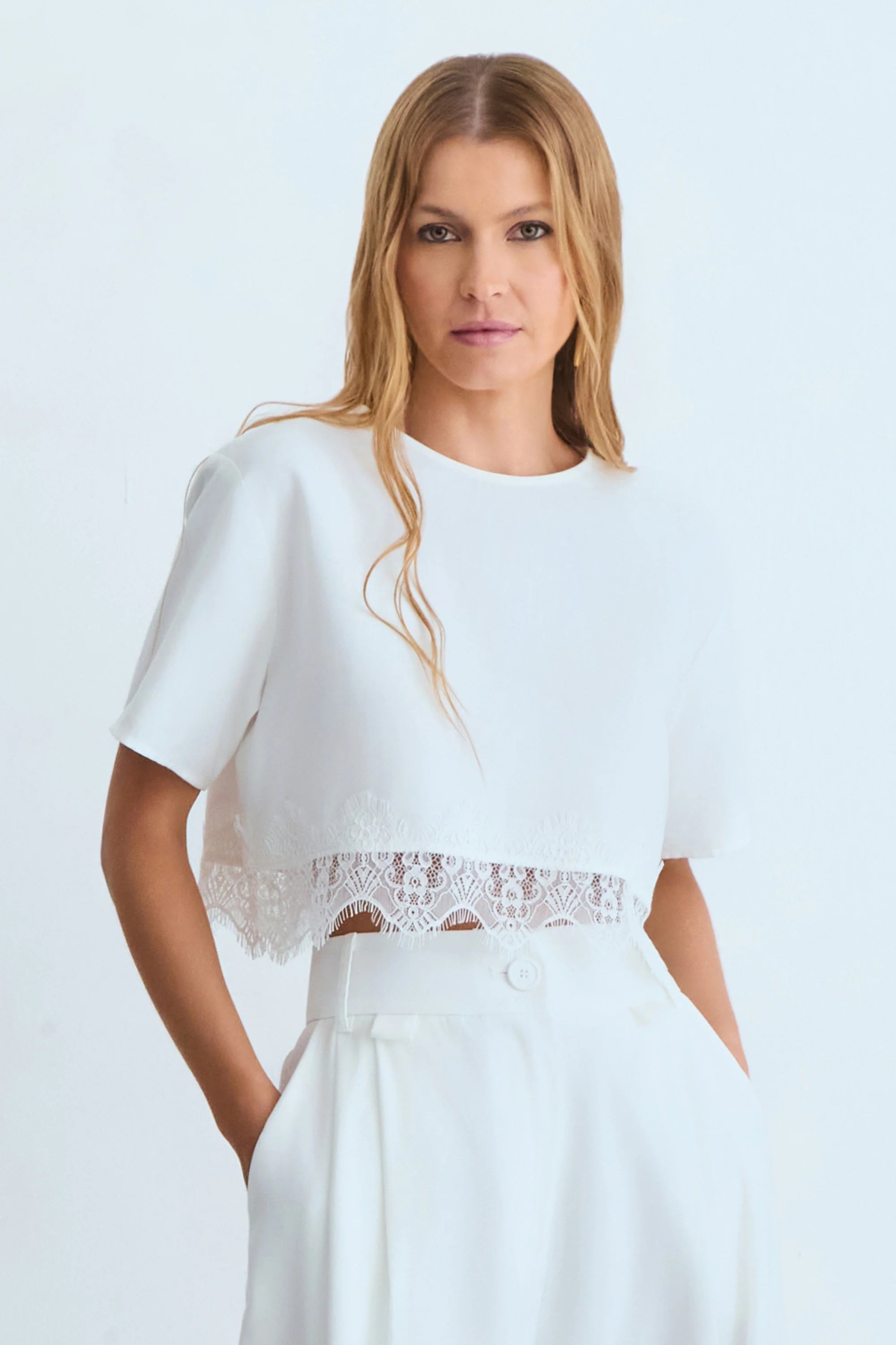 Off-white fluid short-sleeve blouse with lace detail at the hem.