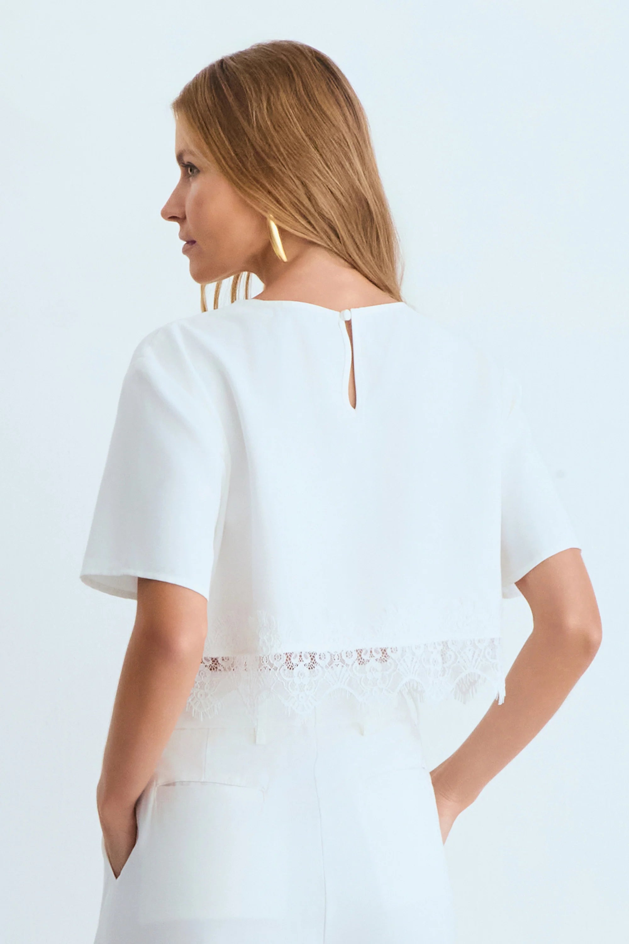 Off-white fluid short-sleeve blouse with lace detail at the hem.