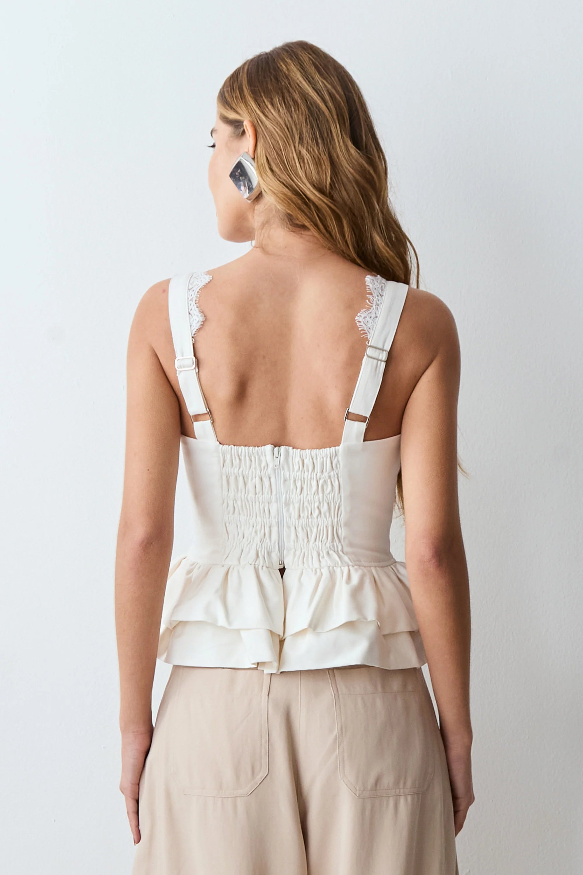 White lace tank top with structured hem, featuring a specific neckline and straps.
